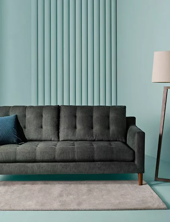 Dark grey sofa in a plain room with bright duck blue walls and floor lamp