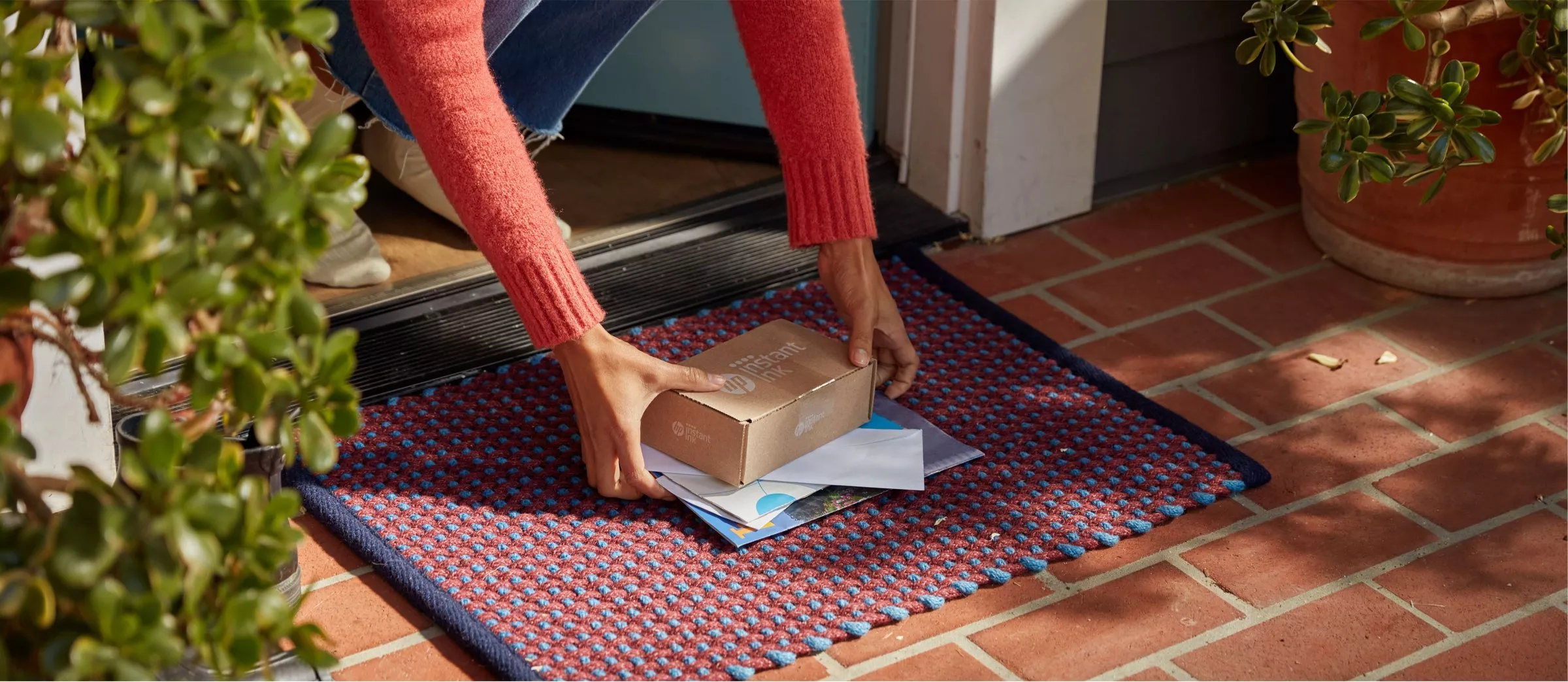 Person picking up a parcel from a doorstep doormat with letters at the front door, home delivery scene