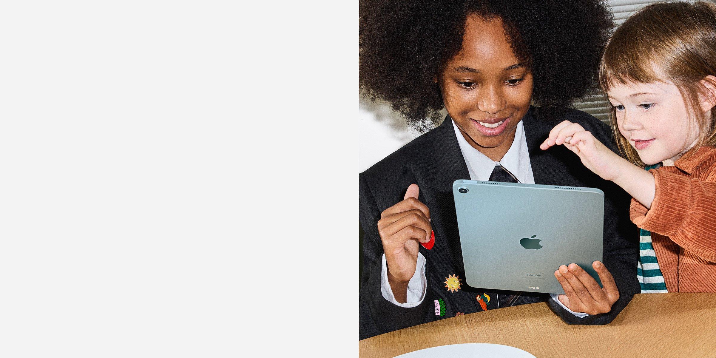 Two children smiling and interacting with an Apple iPad Air.