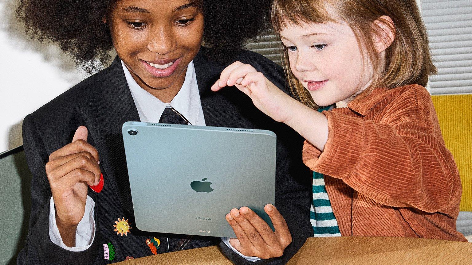 Two children smiling and interacting with an Apple iPad Air.