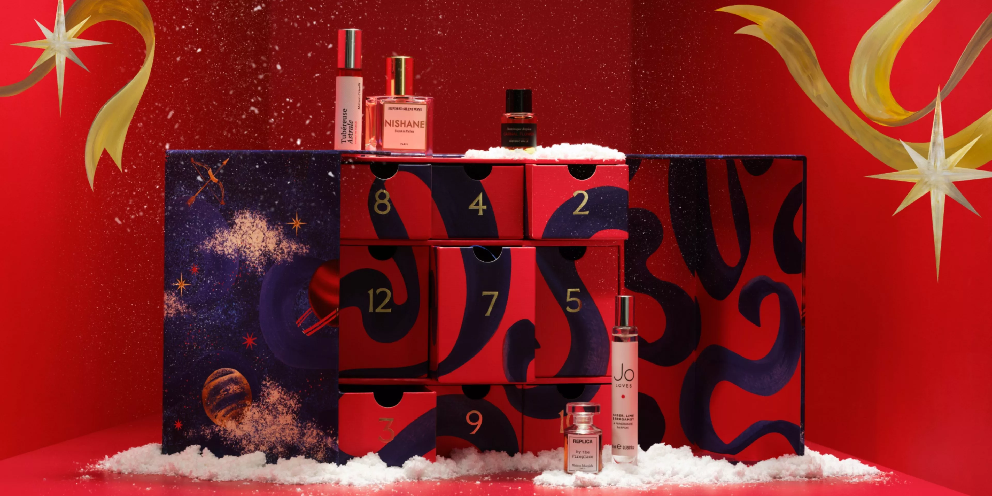 Festive perfume advent calendar gift box with numbered drawers, fragrance bottles and faux snow on red backdrop