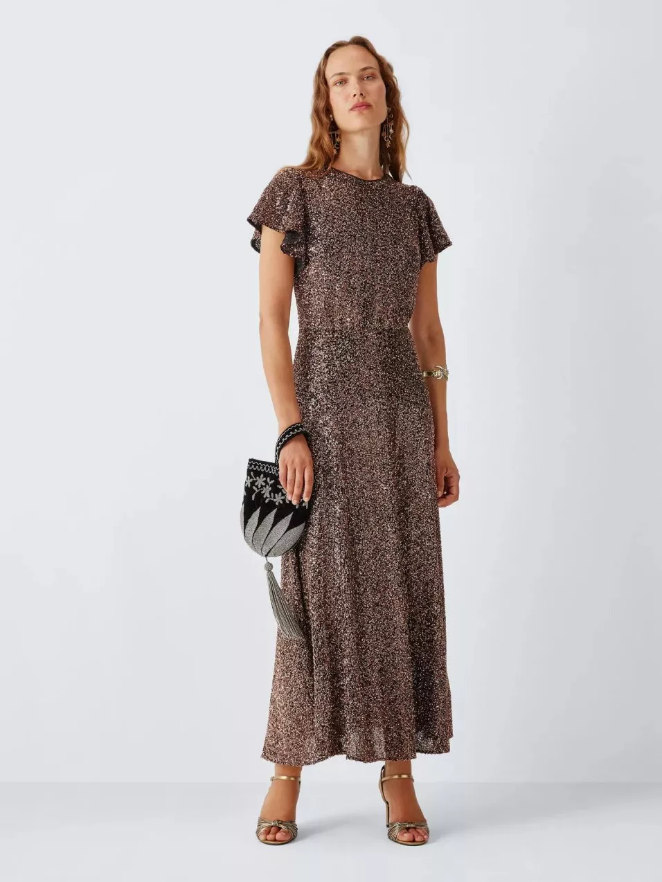Woman modelling bronze sequin midi dress with flutter sleeves, holding beaded clutch and wearing strappy heels.