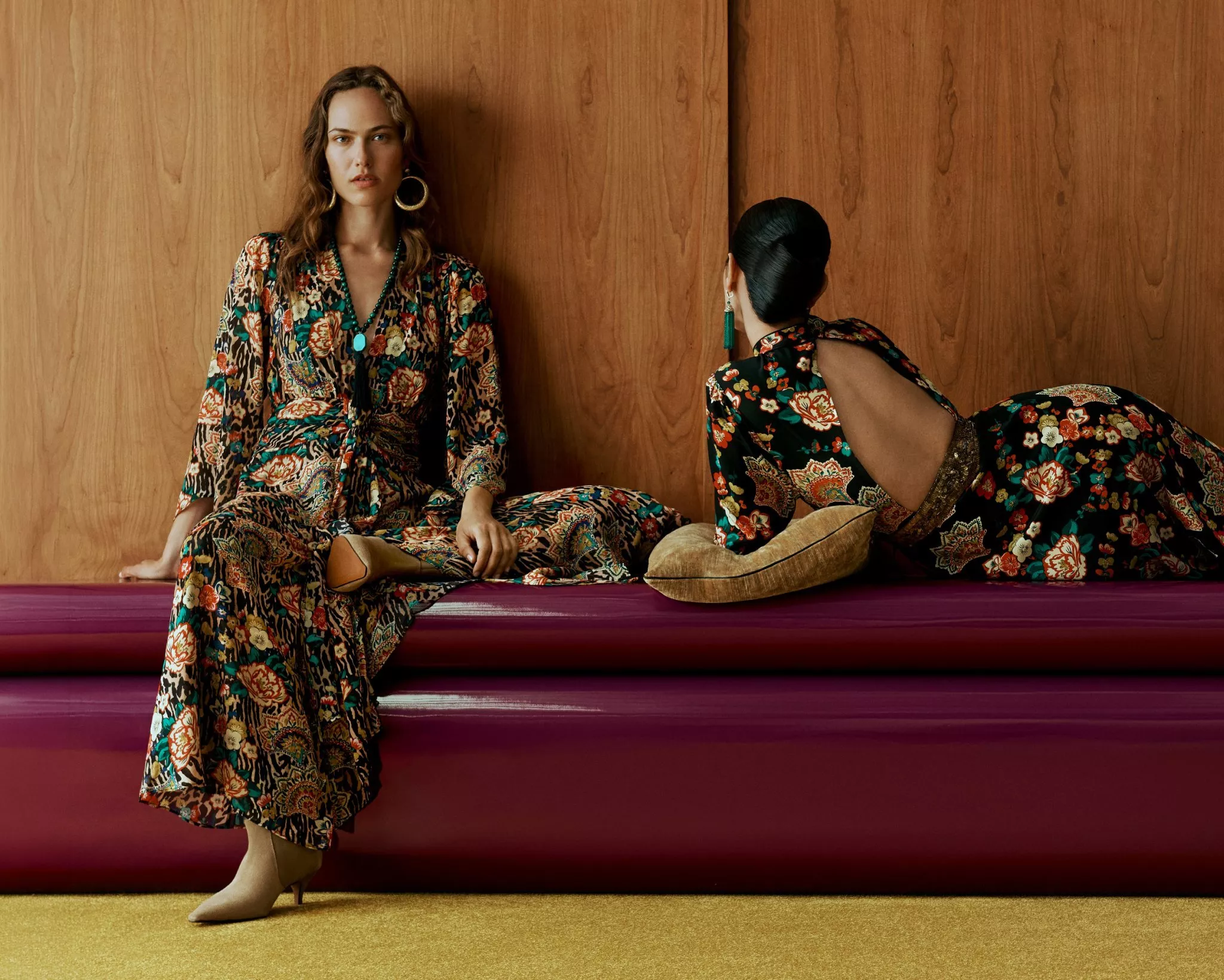 two women in rixo clothing on a red bench