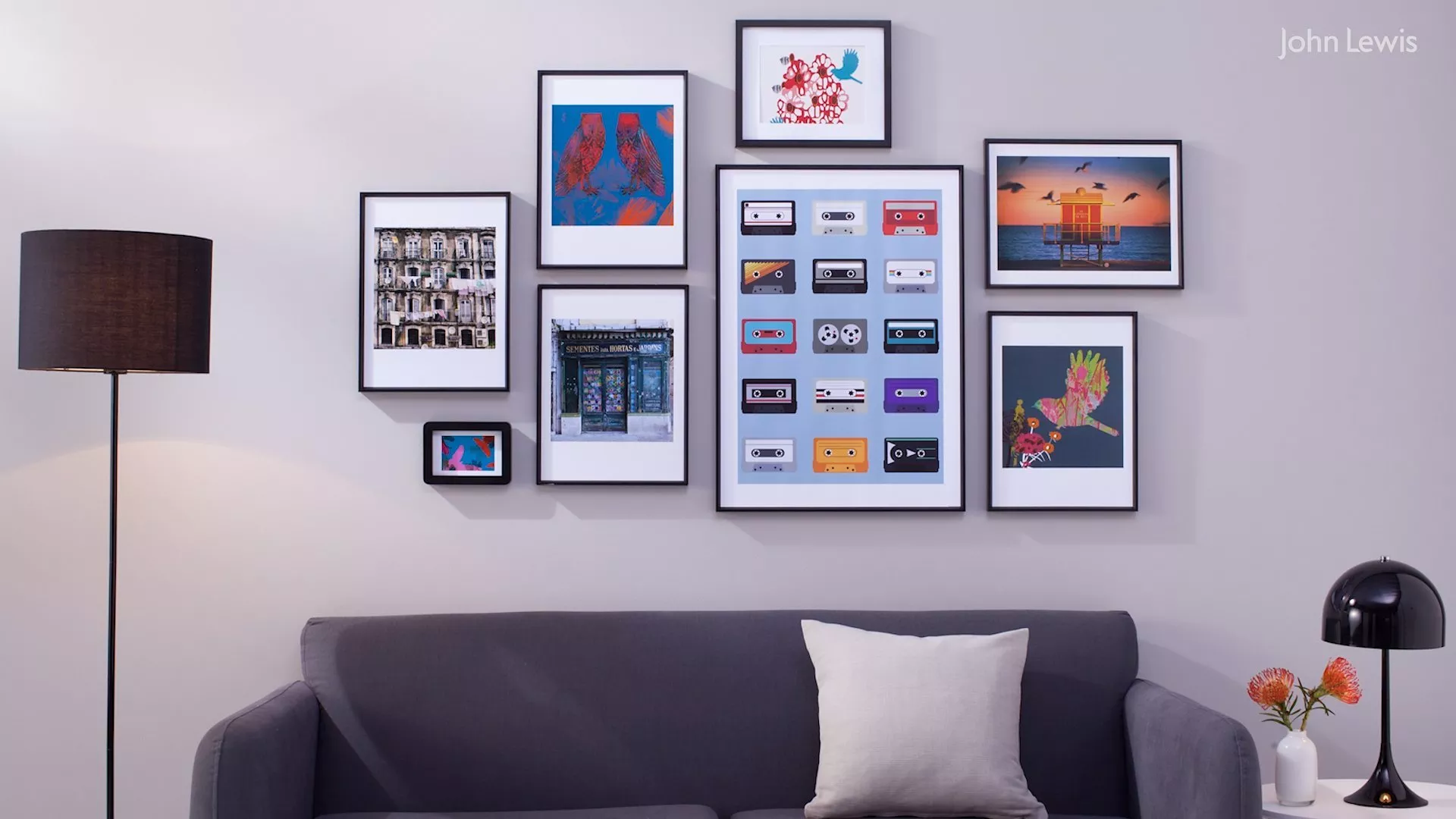 Gallery wall of framed prints above grey sofa with floor lamp and side table, modern living room décor inspiration