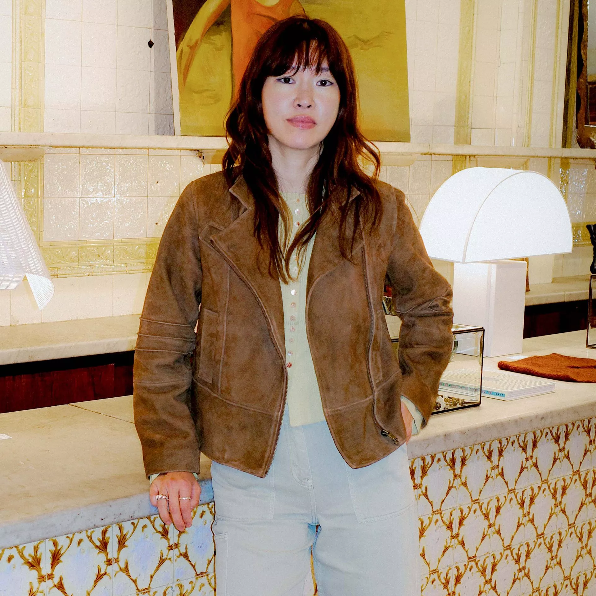 Person in brown leather jacket holding Bowers & Wilkins over-ear wireless noise-cancelling headphones outdoors