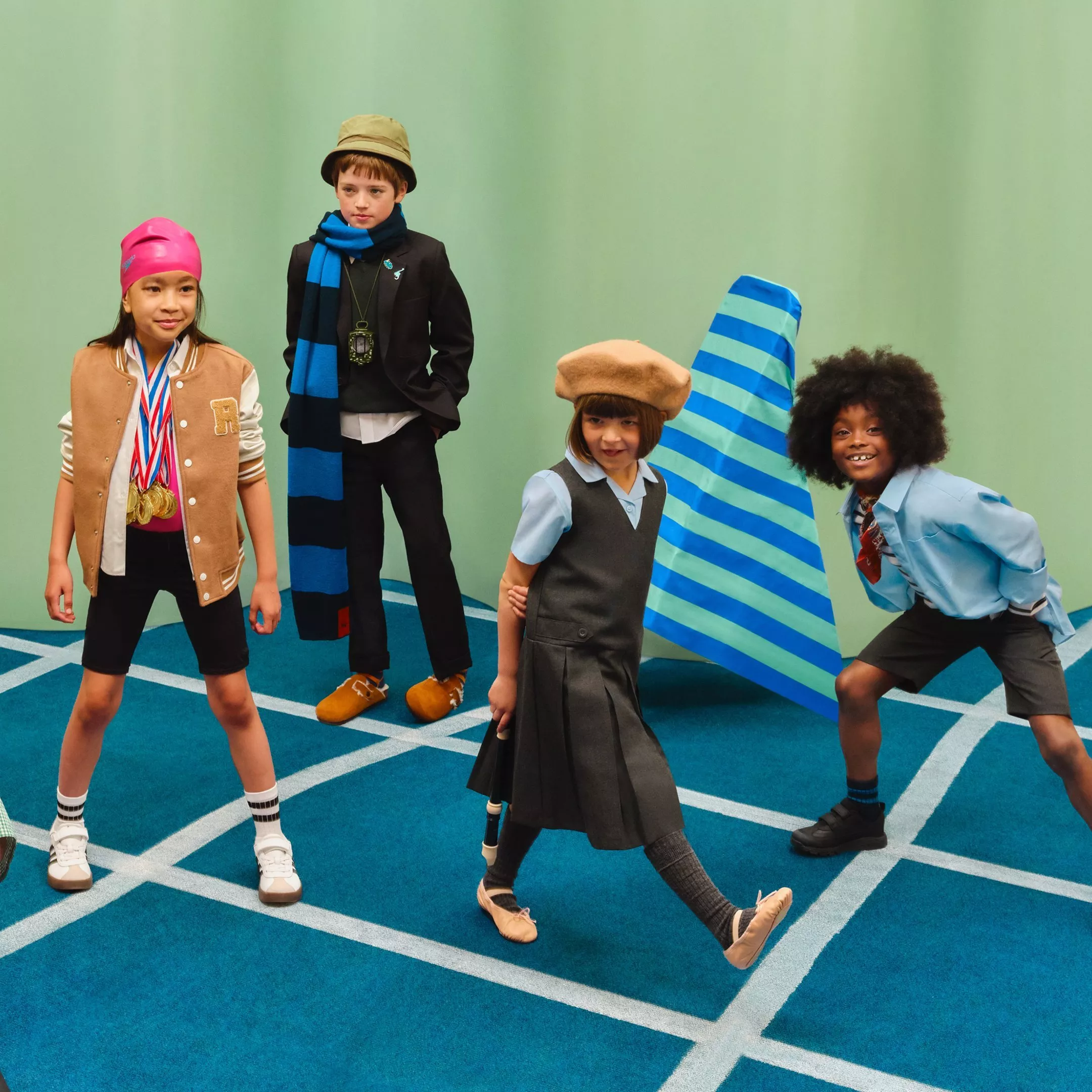 Four children in colourful outfits posing on a blue carpet, playful kids fashion editorial shoot indoors