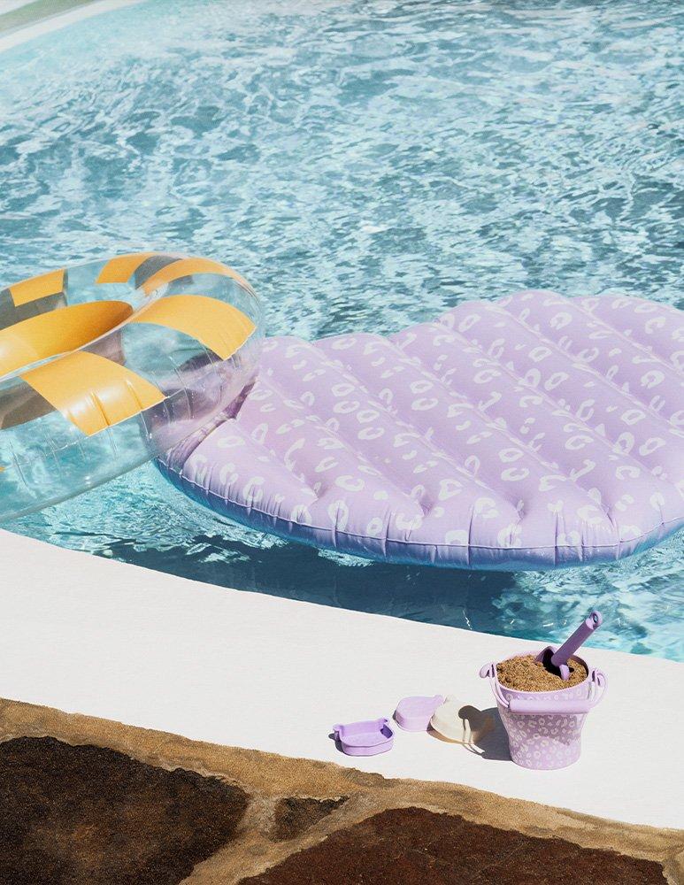Inflatable hoop and lilo floating in a swimming pool, with a spade and bucket of sand on the poolside