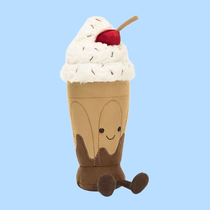 Plush milkshake soft toy with whipped cream, a cherry on top, and a smiling face with dangling legs
