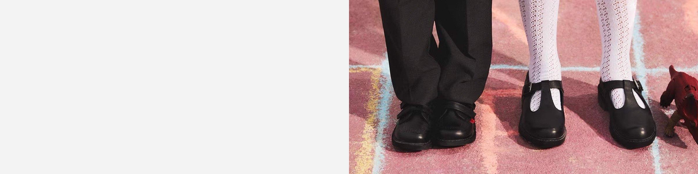 Close-up of two pairs of legs and feet, one in boys shoes and black pants, the other in girls white fishnet stockings and black shoes
