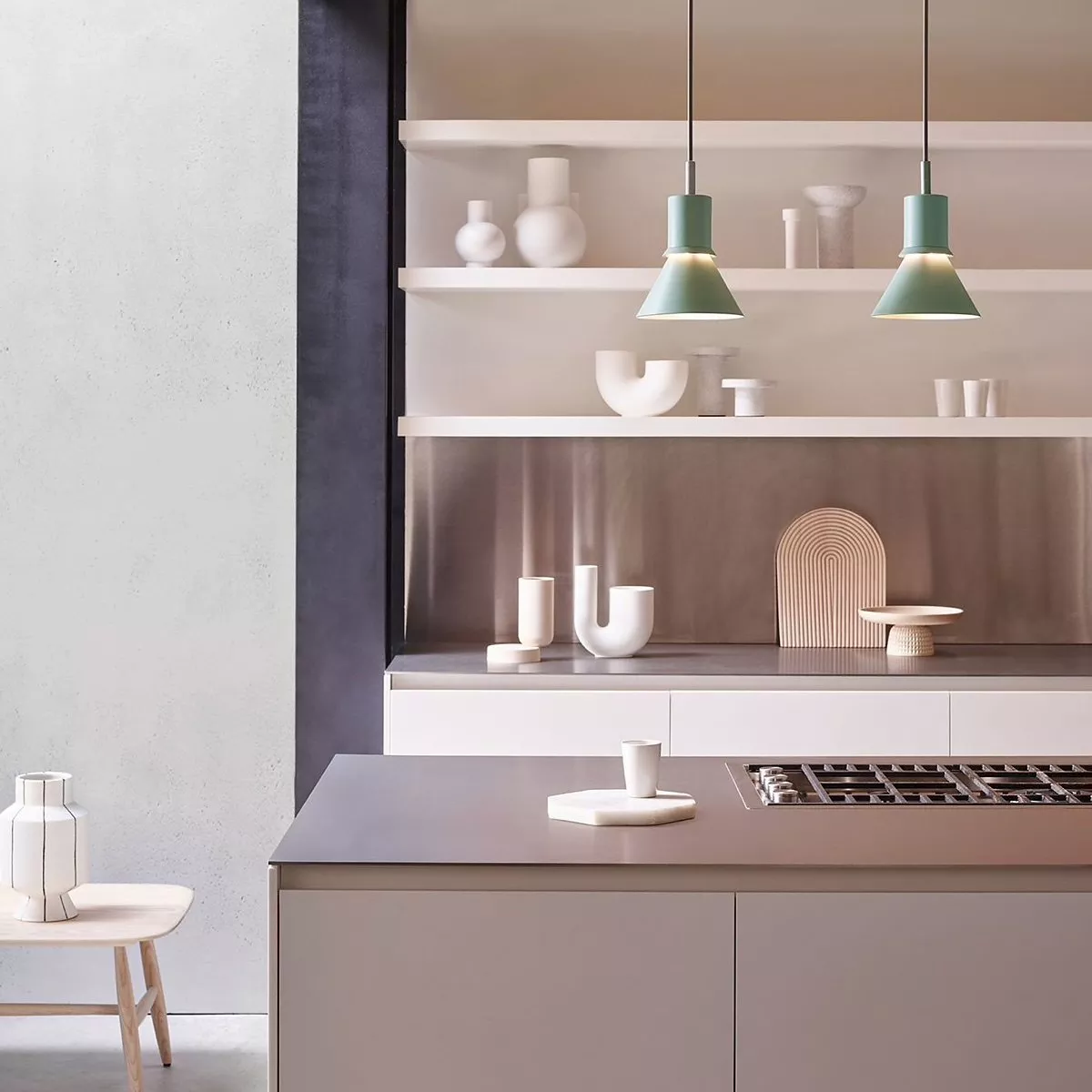 Modern minimalist kitchen with open shelves, white ceramics and green pendant lights above a sleek island hob