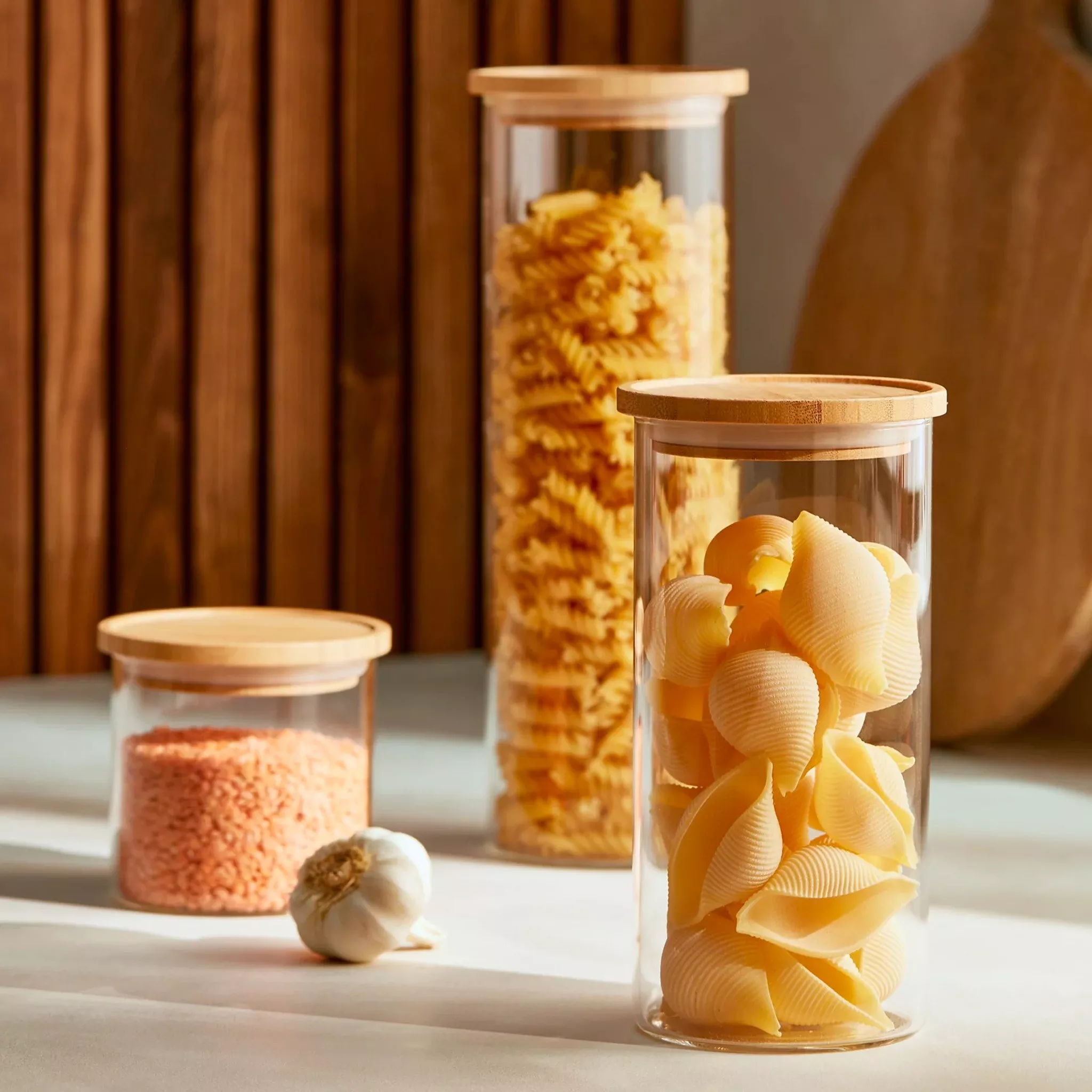 3 glass jars with wooden lids filled with pasta varieties