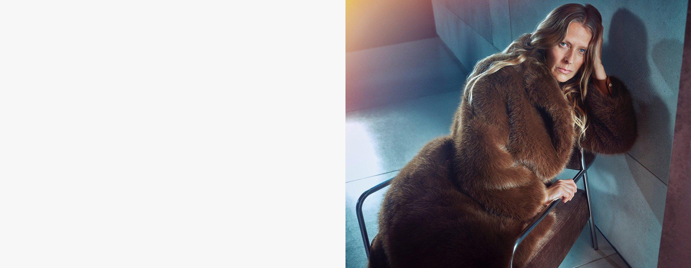 Woman in brown fur coat sitting on chair