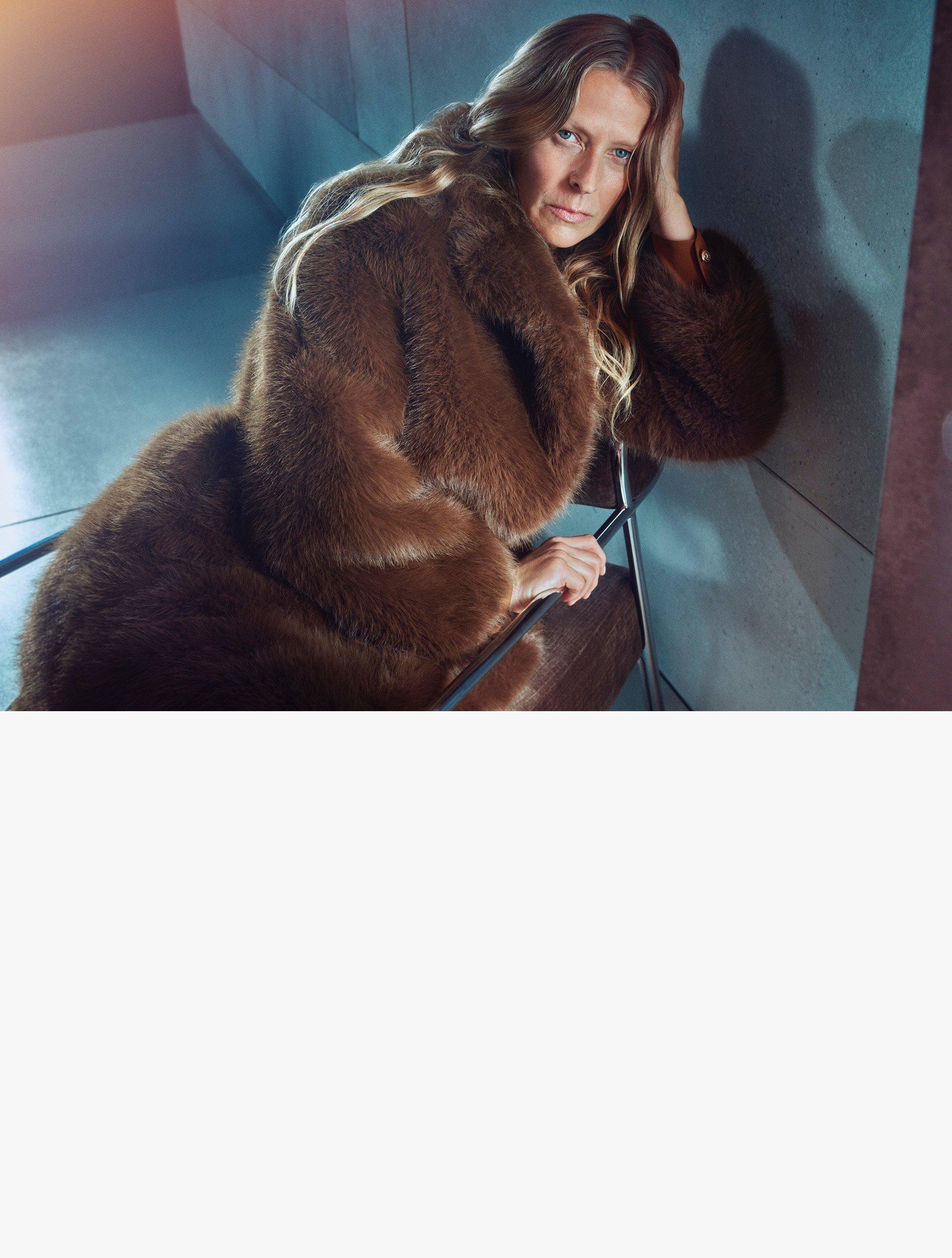 Woman in brown fur coat sitting on chair