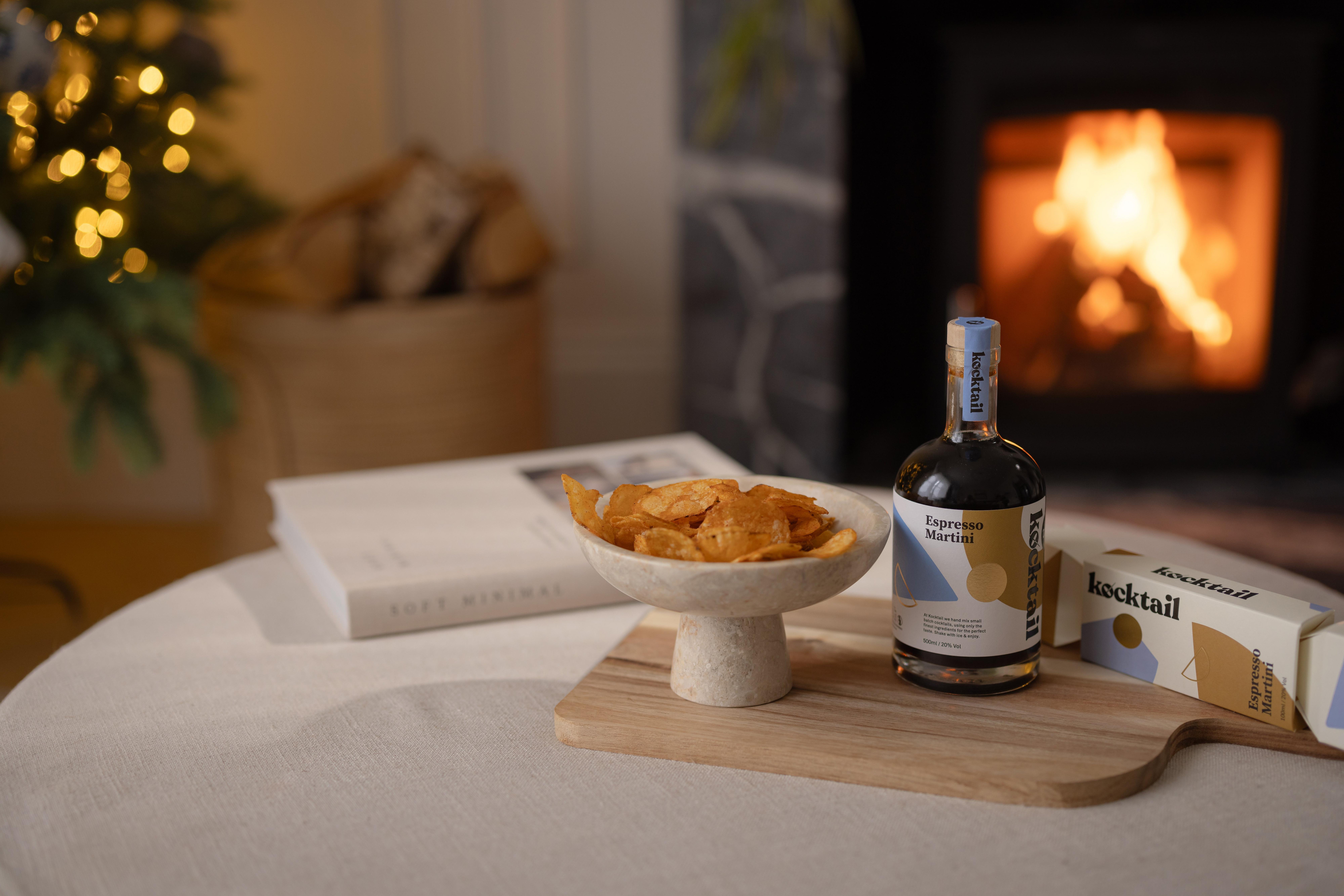 kocktail bottle next to a book with a wood fire behind