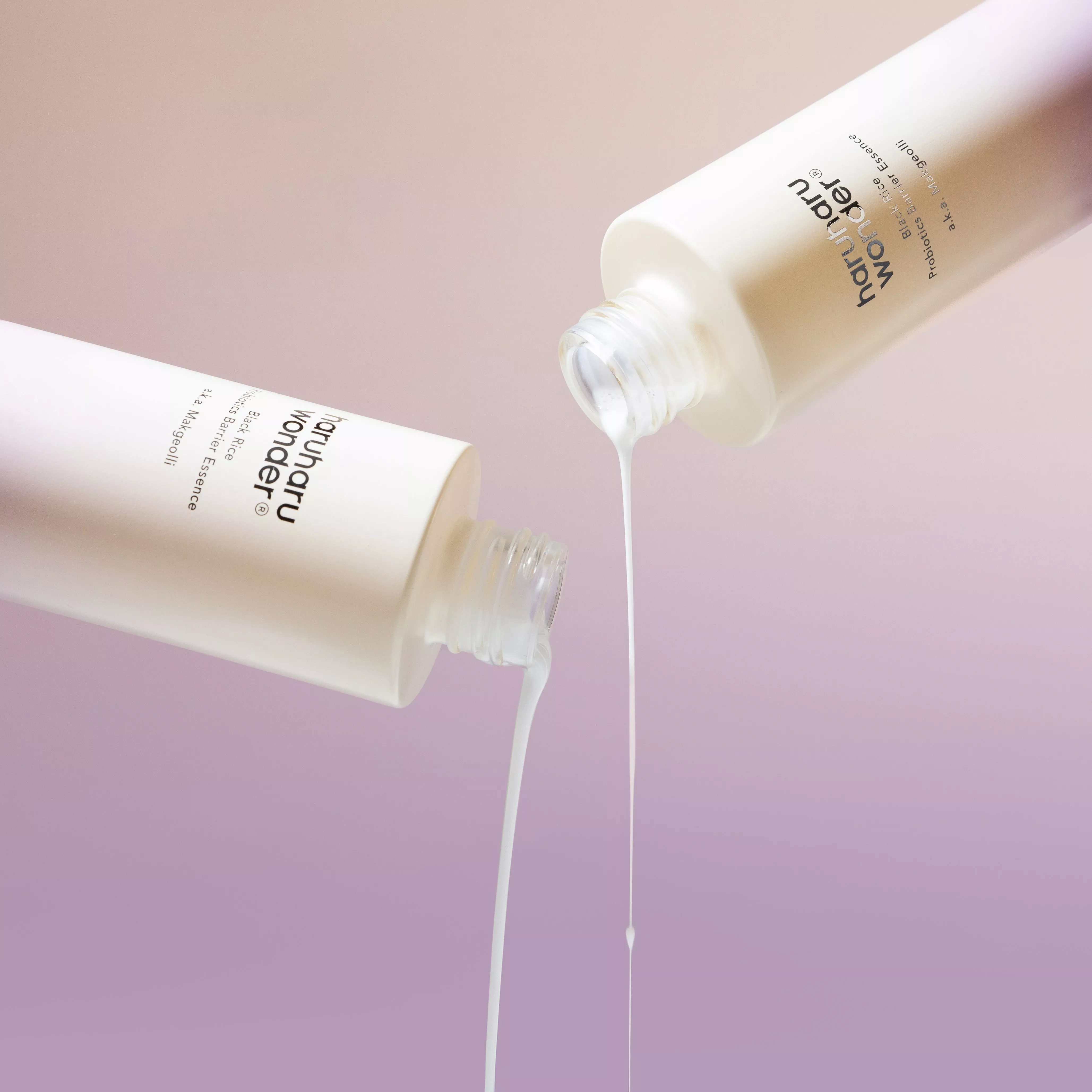 Two bottles of Haruharu Wonder Black Rice Probiotics Barrier Essence, creamy serum pouring on pastel background