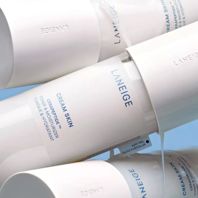 Laneige Cream Skin toner and moisturiser bottles on blue background, minimalist Korean skincare packaging