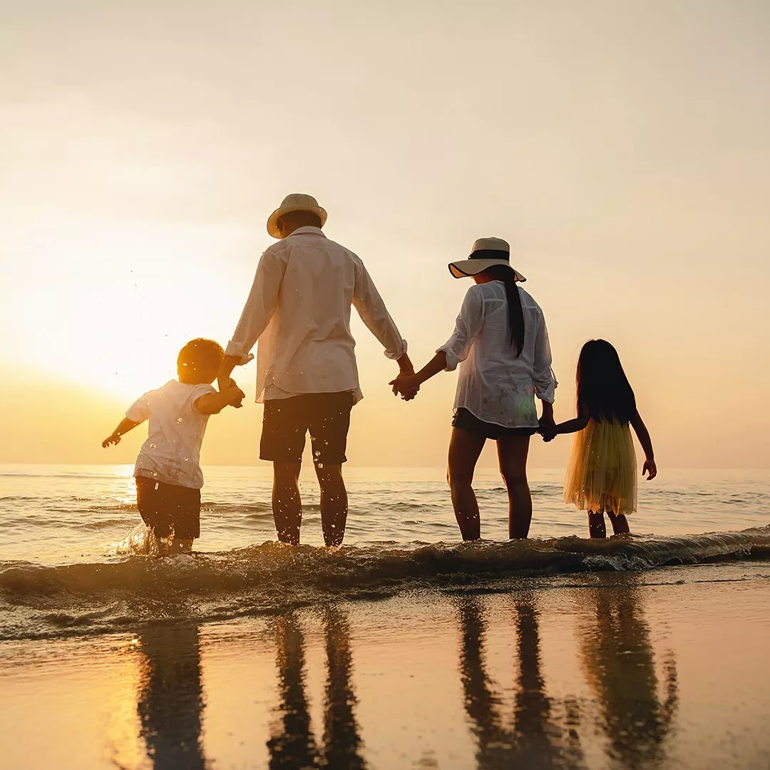 Family holding hands in a row whilst paddling in the sea 