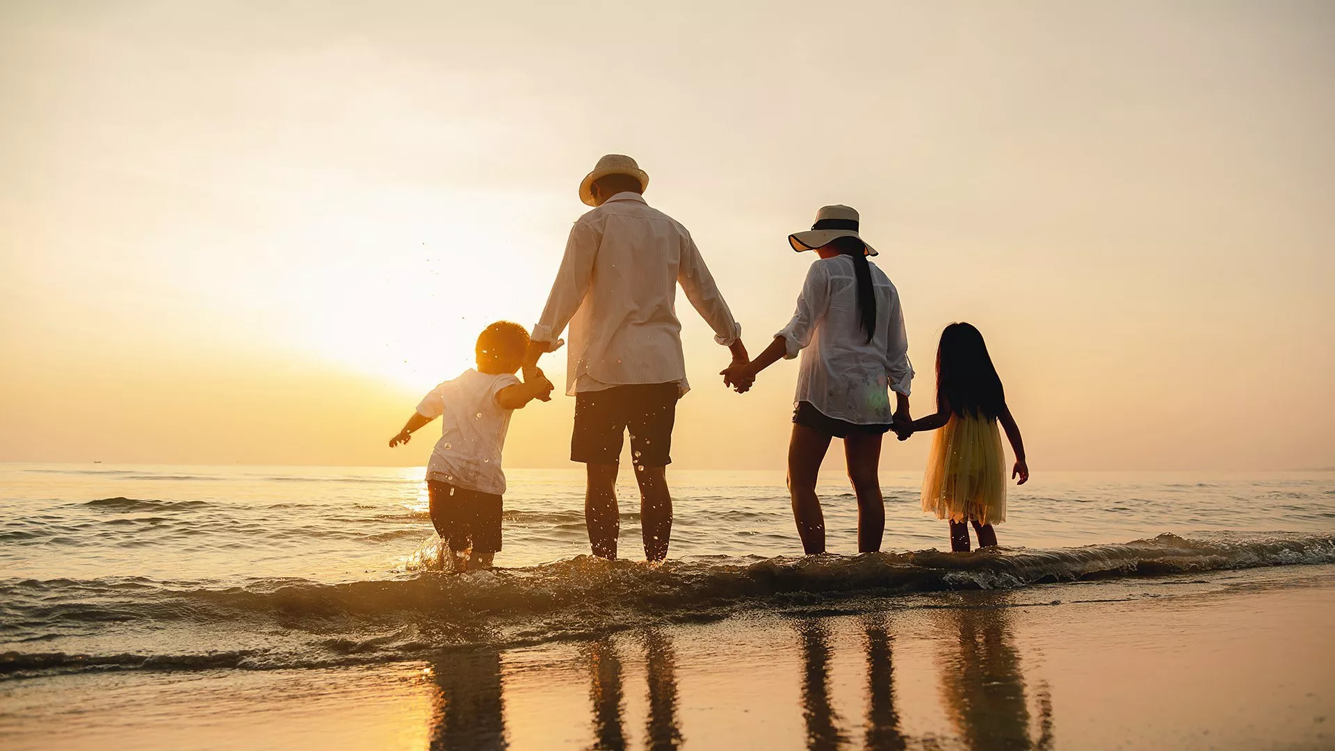 Family holding hands in a row whilst paddling in the sea 