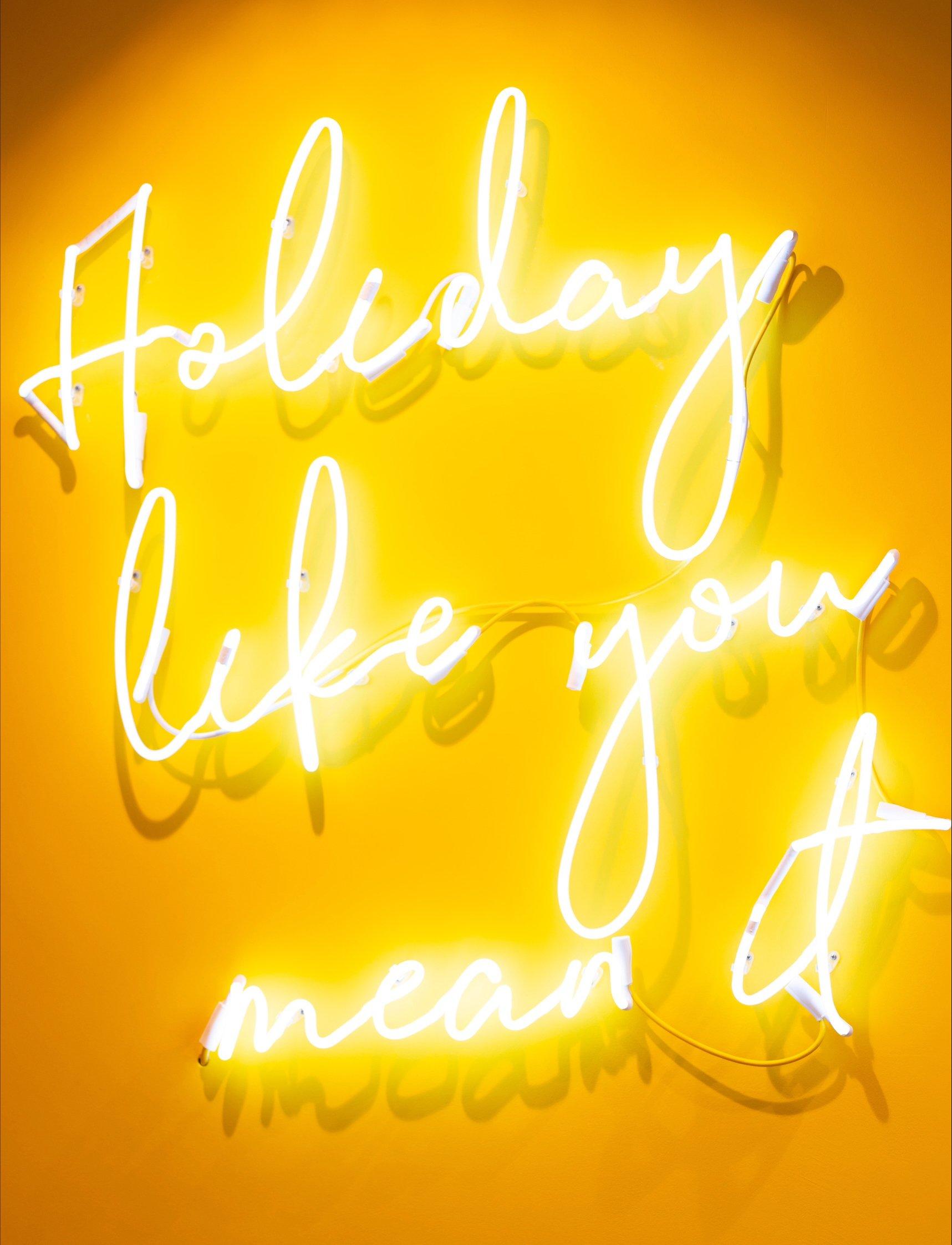 Kuoni neon sign with the words holiday like you mean it