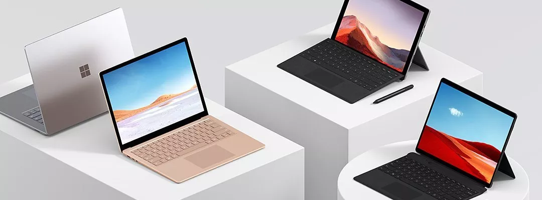Microsoft Surface laptops and 2-in-1 tablets on white plinths, showcasing colourful screens and keyboards