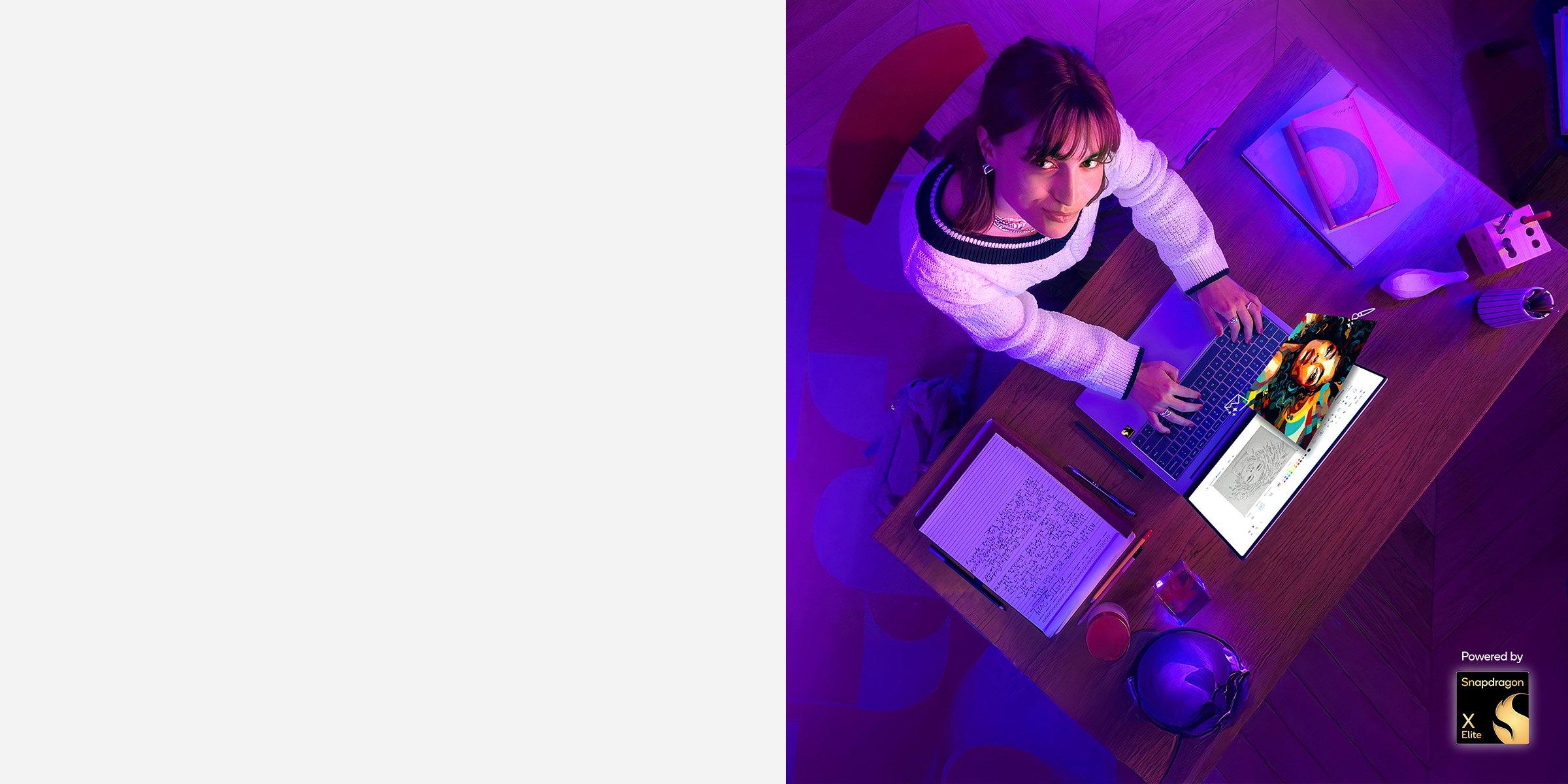 Overhead view of woman sitting at desk with laptop, looking up