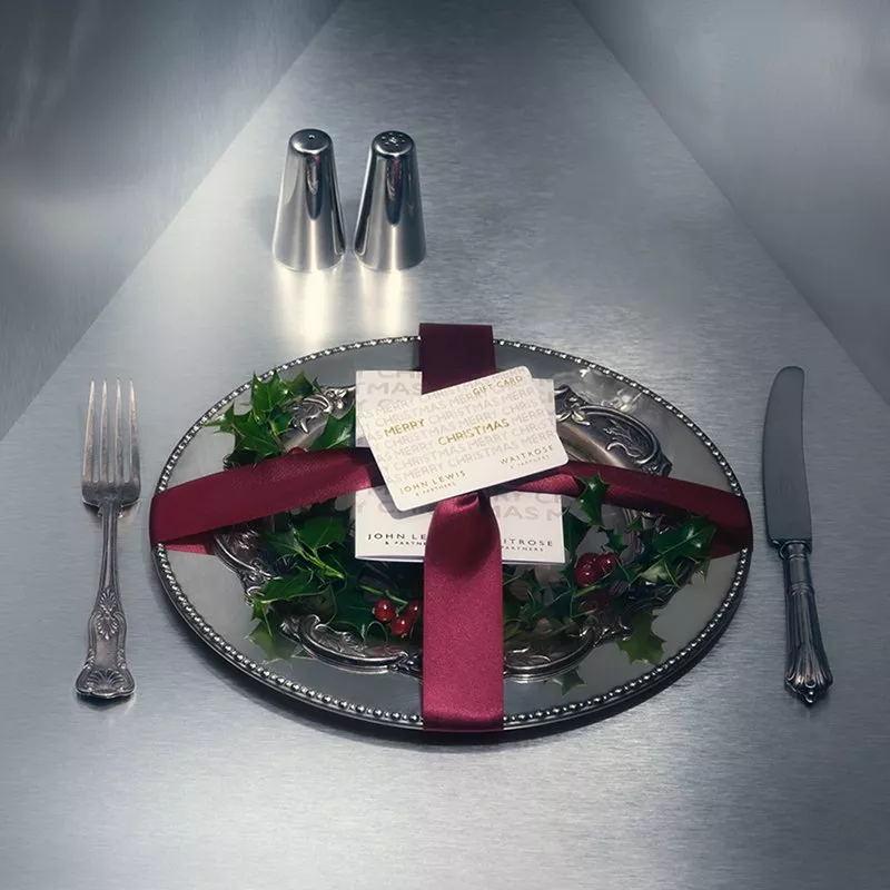 A gift voucher card sitting on a silver plate with a knife and fork next to it
