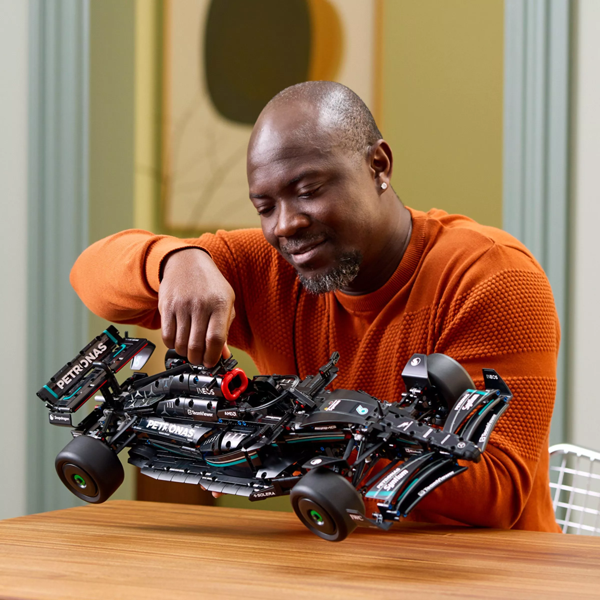 man holding the LEGO Speed Champions 77244 Mercedes-AMG PETRONAS F1 Team W15 E Performance Race Car Set