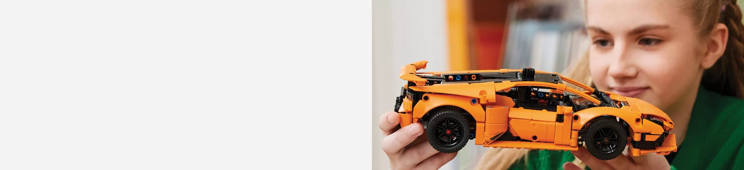 picture of a girl holding a orange Lego car