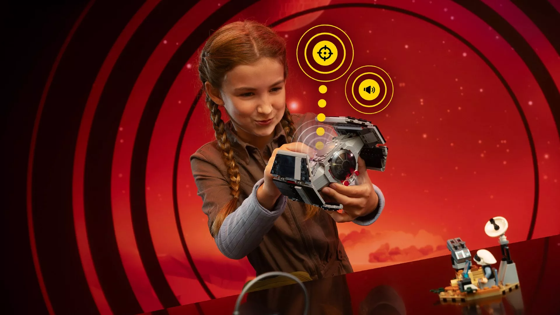 A child plays with a Star Wars LEGO ship against a red, futuristic background with digital icons.