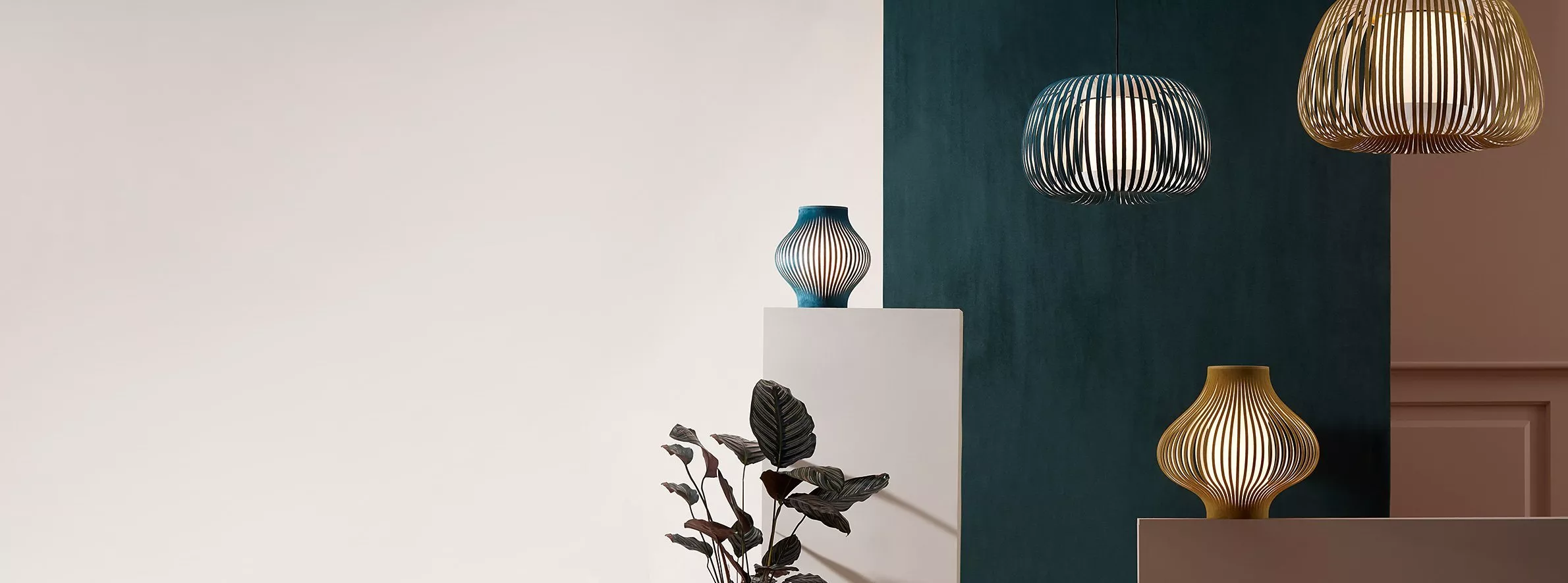 Modern pendant lights and sculptural table lamps in a minimalist interior with teal wall and neutral décor