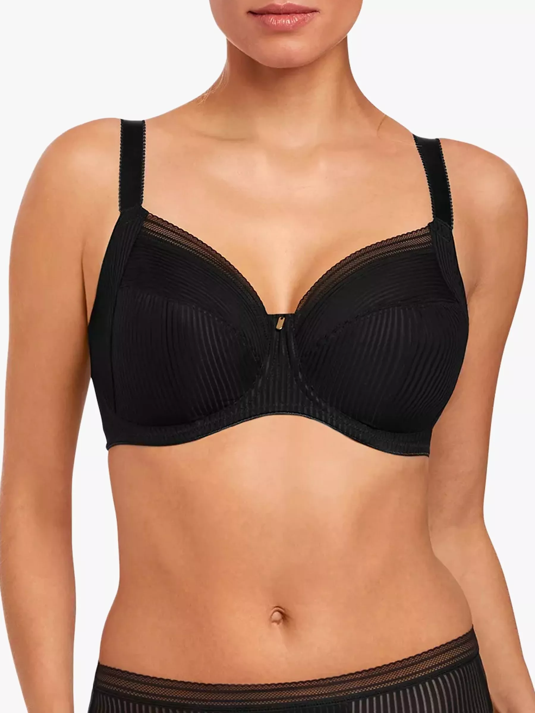 A woman models a black underwired bra with ribbed detailing and adjustable straps against a white backdrop.