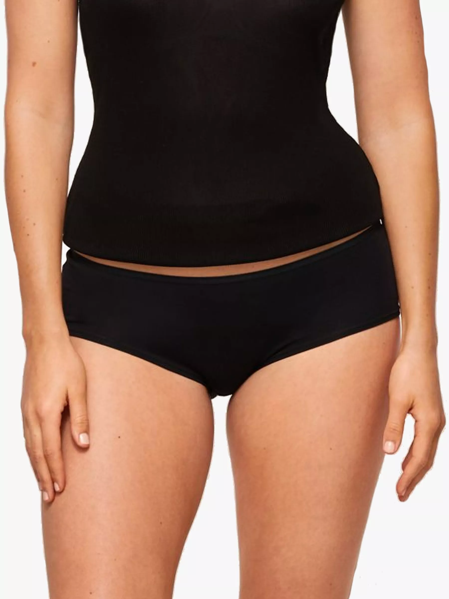 Model wearing black high-waisted  briefs, worn with black tank top