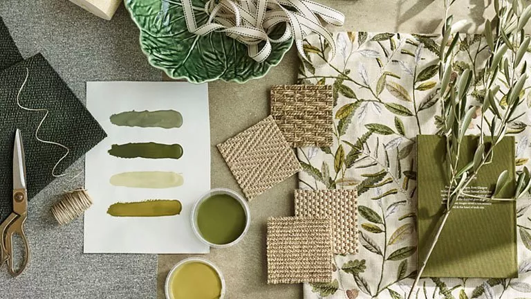 Green themed paint and fabric swatches amongst scissors, string and ribbon.