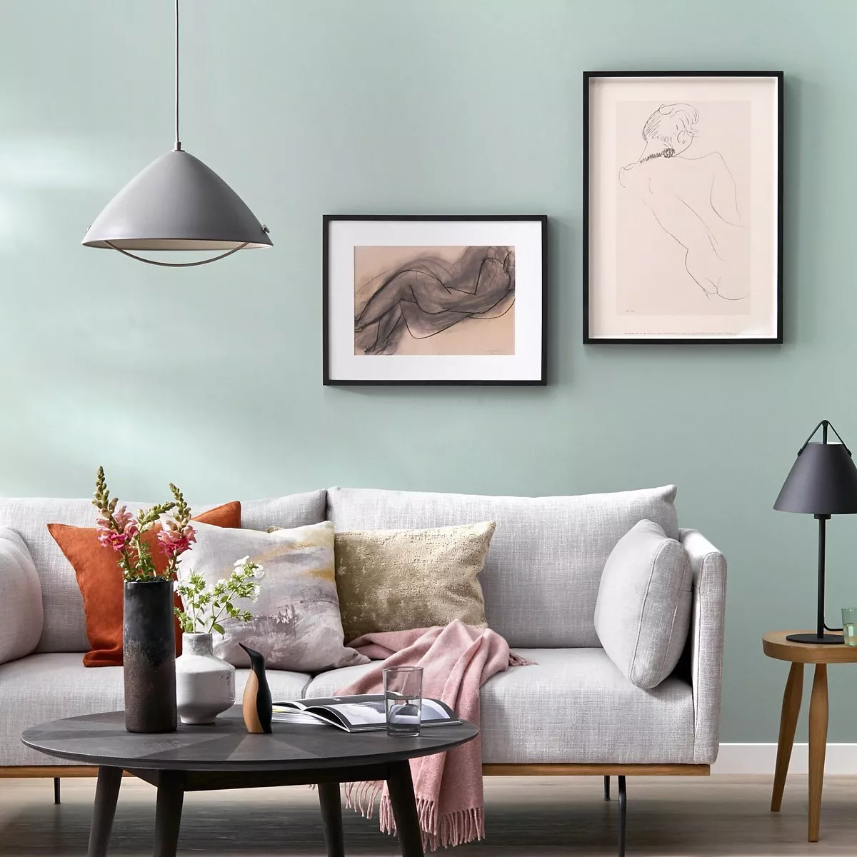 Modern sideboard styling with blue ceramic vases, table lamp and books against a pale blue wall background