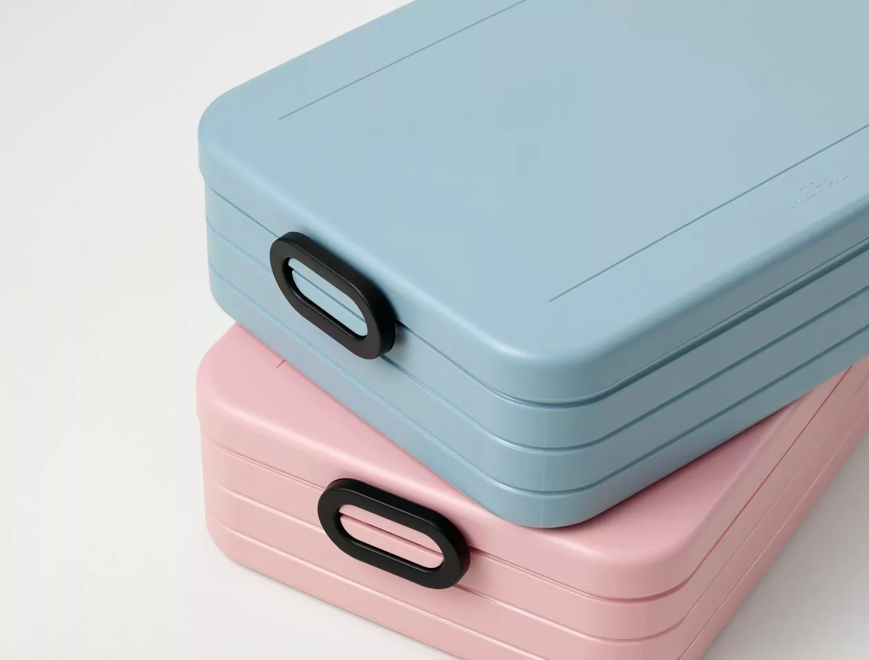 Stacked pastel blue and pink plastic storage boxes with black handles, minimalist organiser containers on white background