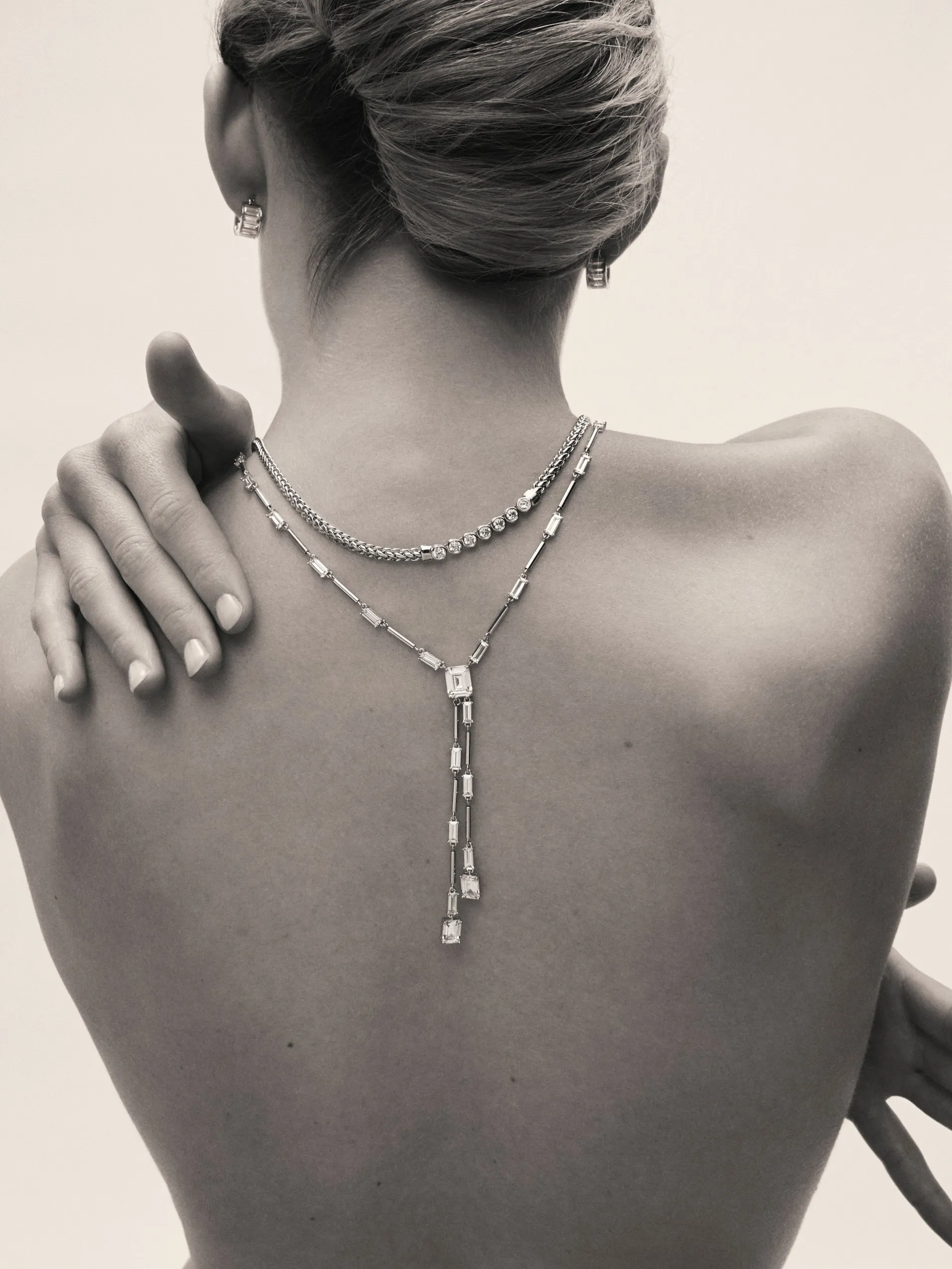 Back view of woman wearing diamond drop necklace and earrings, elegant fine jewellery portrait in monochrome