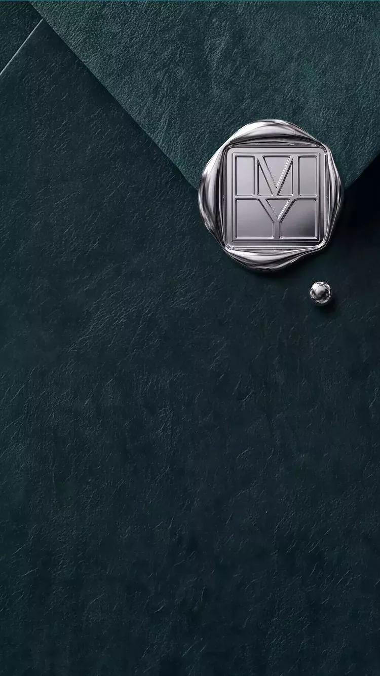 Silver MY monogram wax seal stamp on dark green textured paper, luxury branding stationery close-up detail