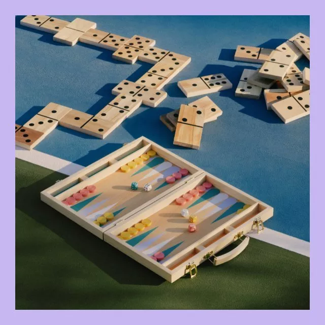 Backgammon set with colourful counters and wooden dominoes on a blue outdoor court surface in sunlight