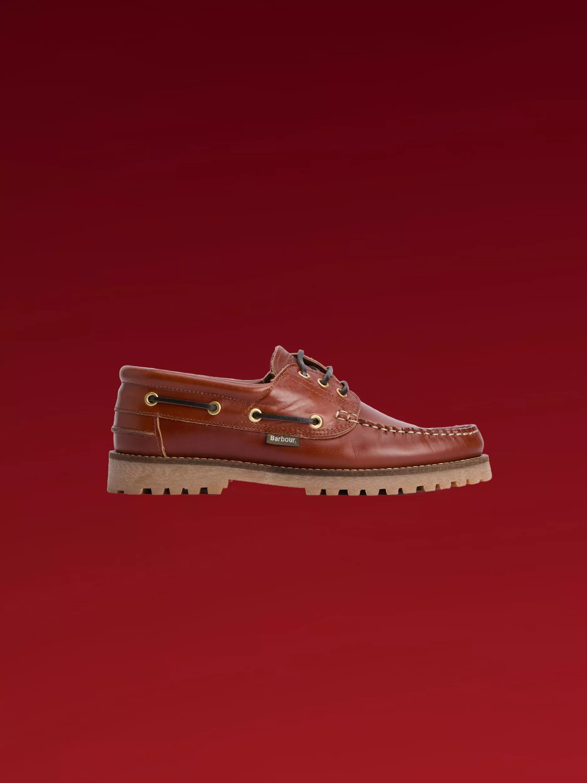 Barbour brown leather boat shoe with lace-up detail and rugged lug sole, side view on deep red background