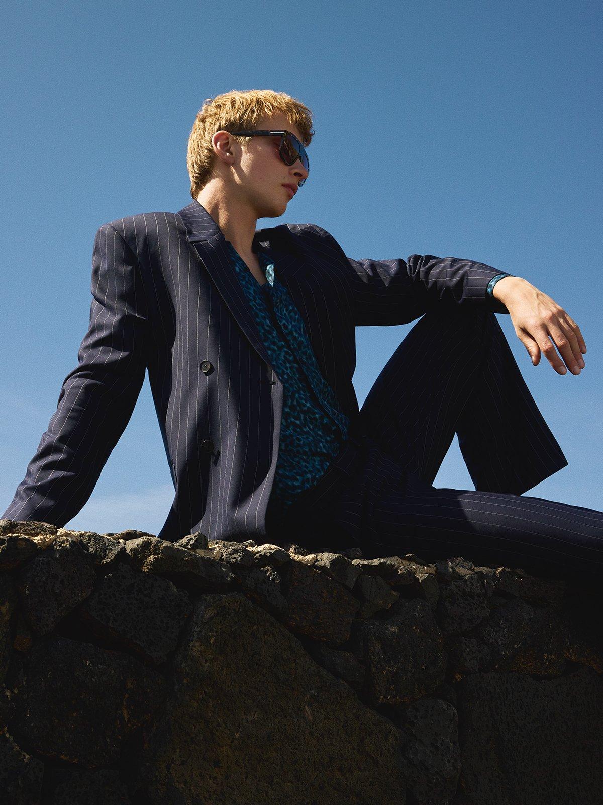 Man in blue suit sitting on a wall in the sunshine