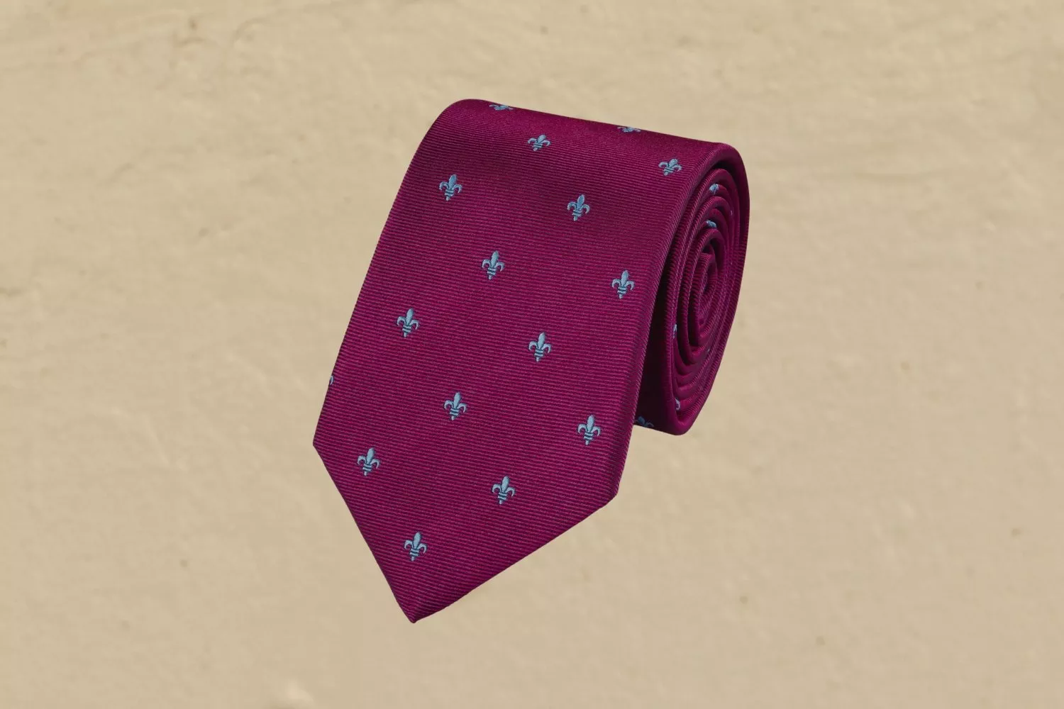 Rolled burgundy silk tie with small blue fleur-de-lis pattern