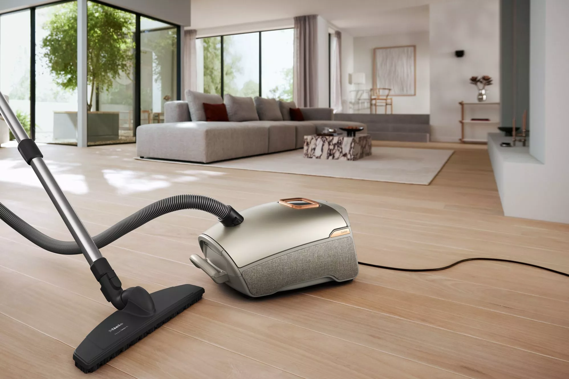 Black Miele cylinder vacuum cleaner with hose, telescopic wand and floor head on white background