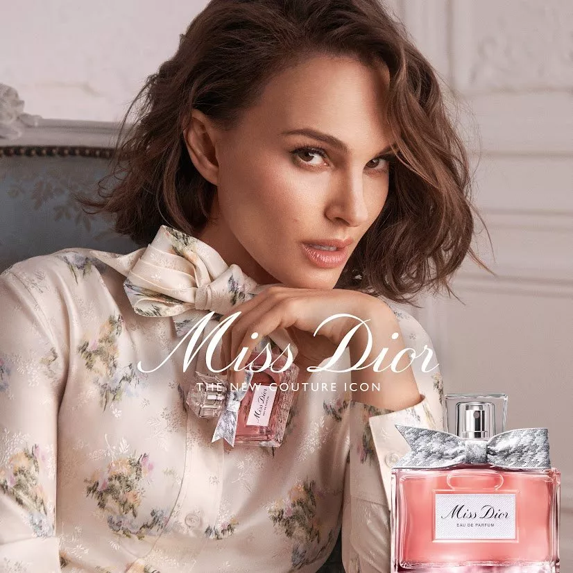 Miss Dior perfume advert featuring a woman in a floral blouse with pink eau de parfum bottle and bow cap