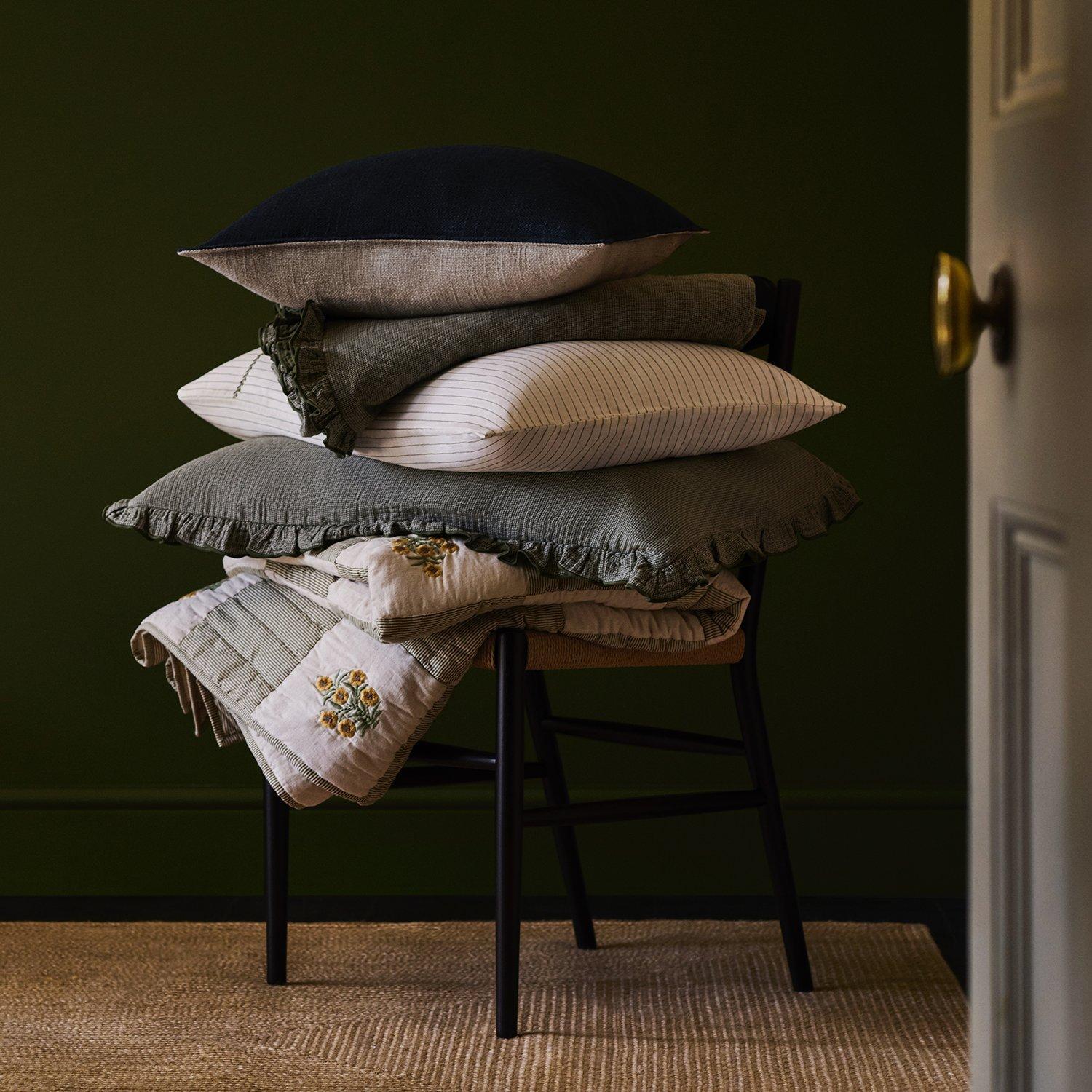 some sheets, duvet and pillow stacked ontop of a chair