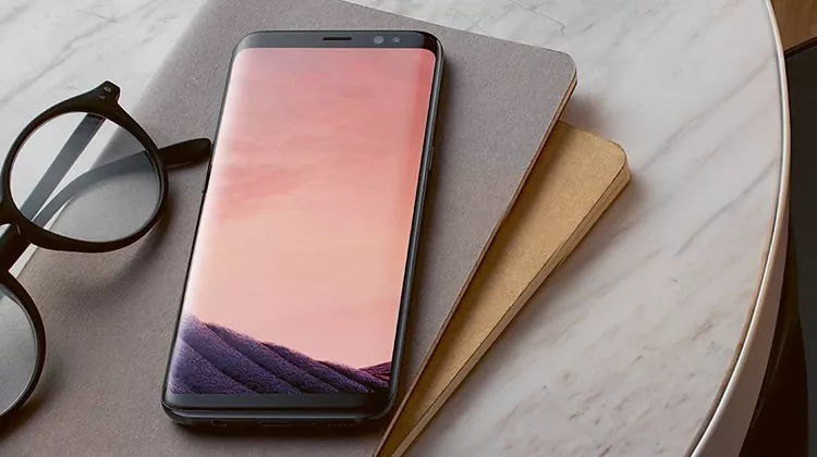 Mobile phone on a table next to books and reading glasses