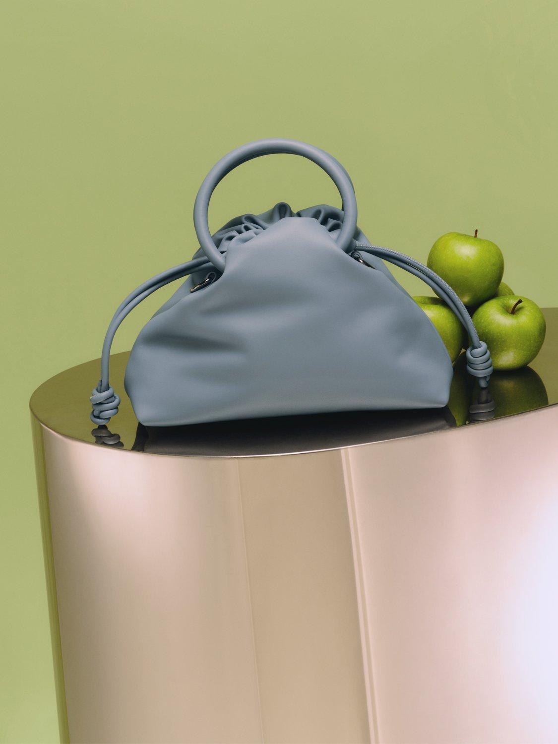 A blue bag sitting on a plinth with apples next to it