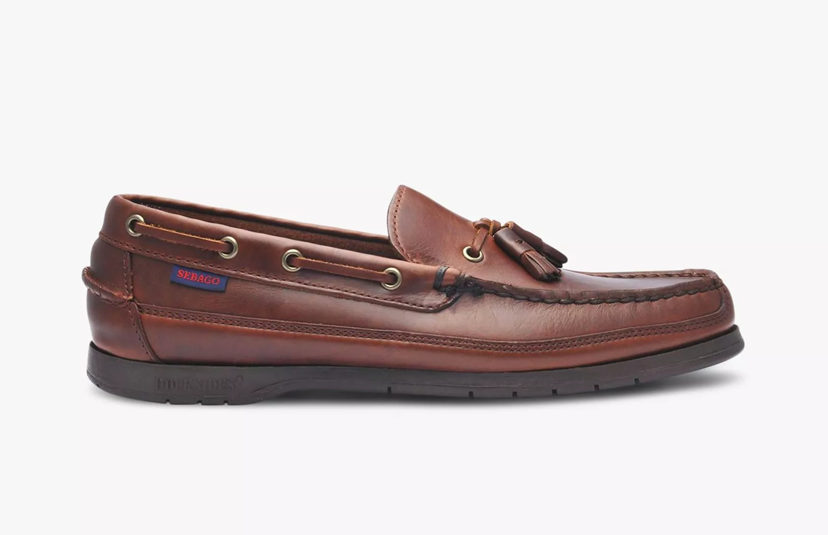 Brown leather tassel loafer boat shoe with stitched moc toe, lace eyelets and rubber sole, side profile view