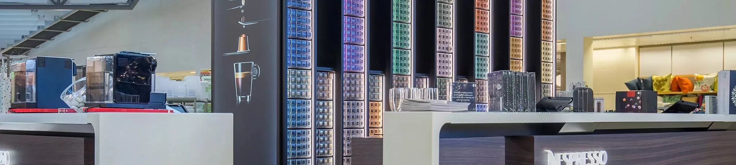 Shelves of coffee capsules behind a coffee counter