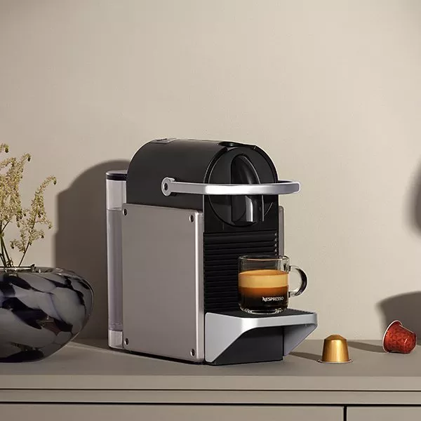Black and silver coffee machine with a freshly made coffee in a glass mug