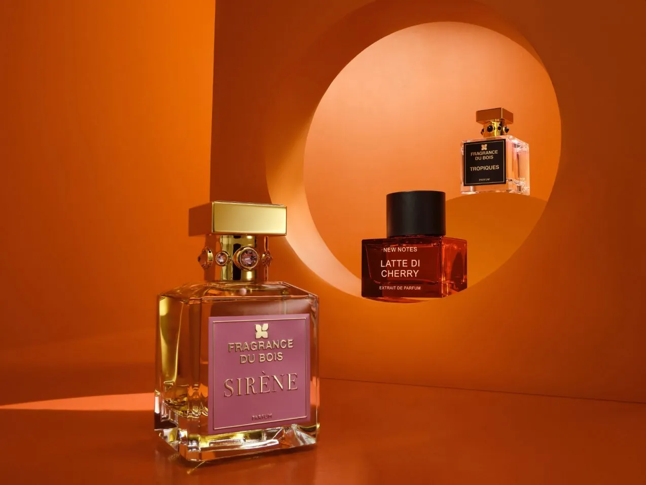 Luxury perfume bottles on orange backdrop, featuring Fragrance Du Bois Sirène and New Notes Latte Di Cherry scents